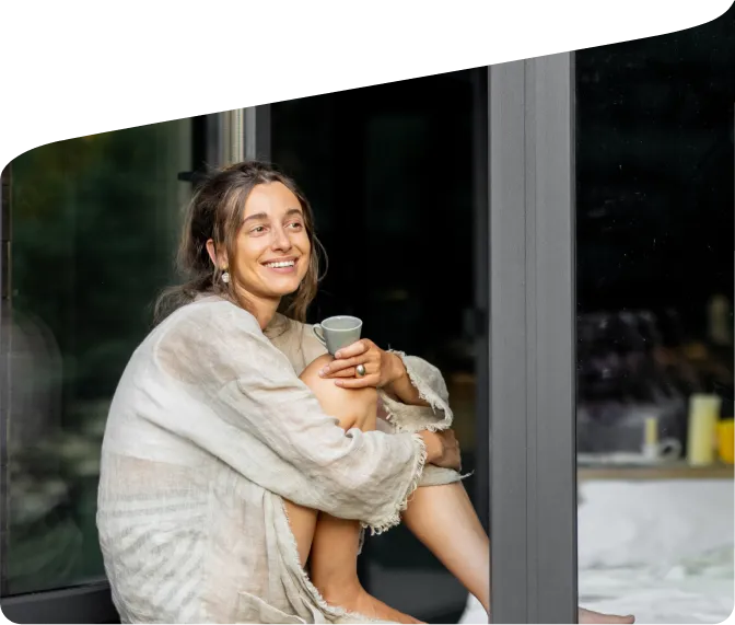 A woman drinking coffee in a doorway.