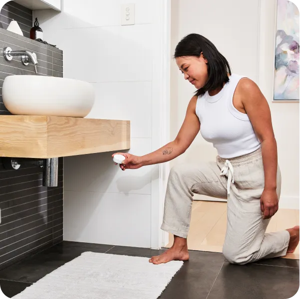 Person placing a smart sensor under a bathroom sink.